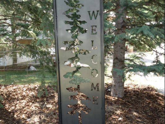 steel welcome sign with pine tree cut out
